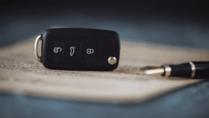 Keys, on a contract with a pen to sign to signify the article titled rent to buy cars